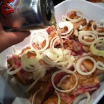 Beer Braised BBQ Ribs layers in baking dish with onions